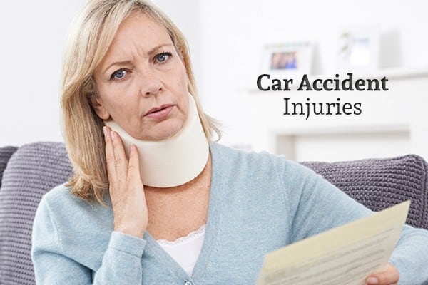 A woman with a neck brace holds a piece of paper beside the words "Car Accident Injuries"