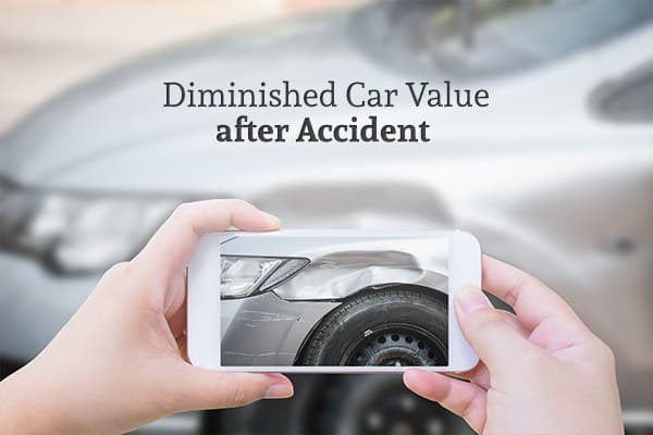 Diminished Car Value after Accident with a car in the background that a person is taking a picture of the damage on with their phone